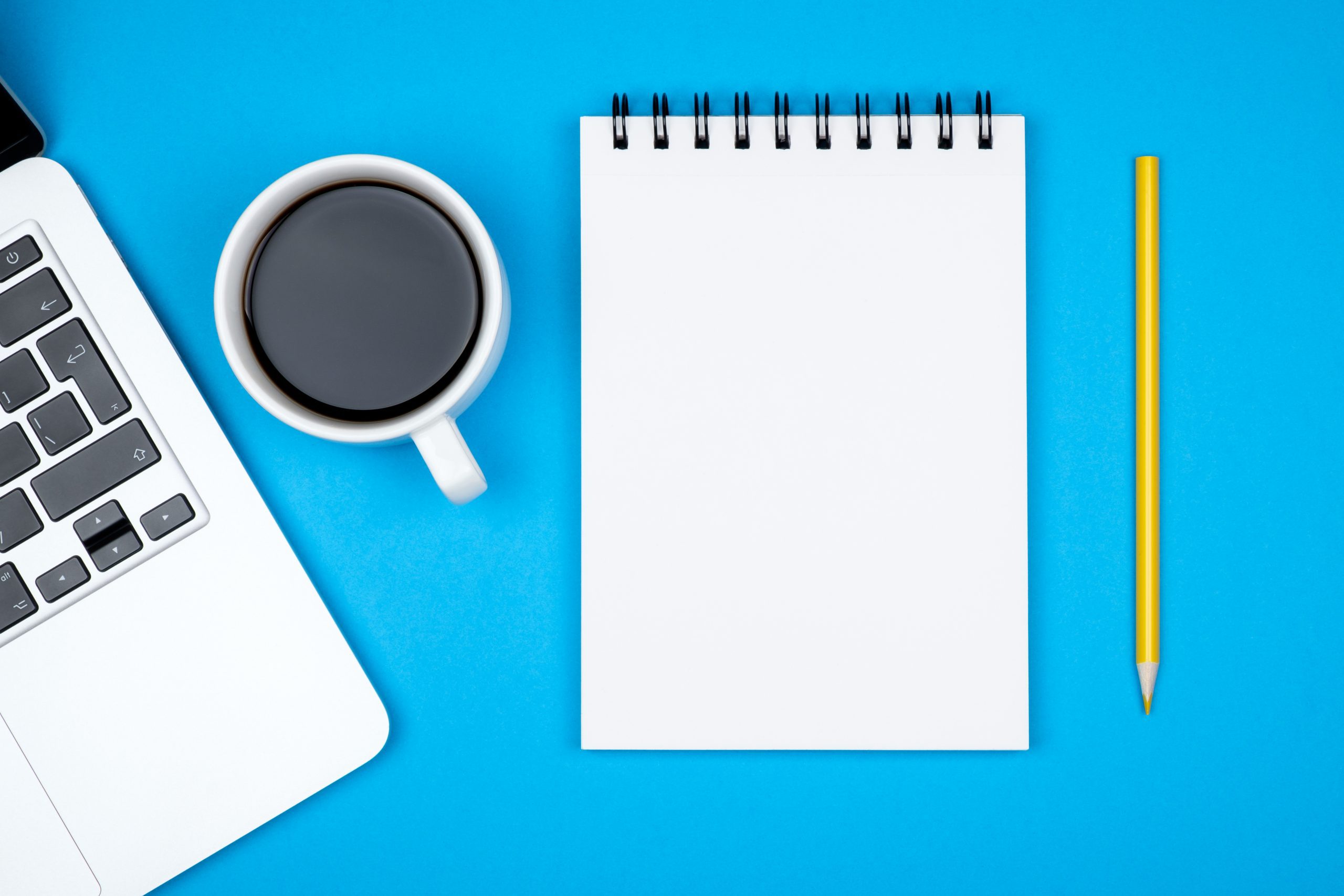 Modern designer office desk table with blank notebook page, laptop computer and cup of coffee Modern designer office desk table with blank notebook page, laptop computer and cup of coffee